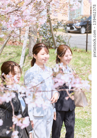 Three young women, new employees, walk under cherry blossoms – an image of a spring induction ceremony and a new life. Three young women, new employees, walk under cherry blossoms – an image of a spring induction ceremony and a new life. 139402378