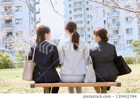 春天,三個身著職業套裝的女士坐在公園長椅上;一群正在尋找工作的大學生的背影;還有盛開的櫻花。 春天,三個身著職業套裝的女士坐在公園長椅上;一群正在尋找工作的大學生的背影;還有盛開的櫻花。 139402394