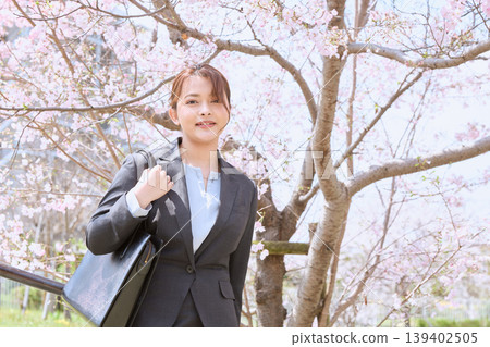 A young woman in a business suit, a new employee, walking under cherry blossoms - an image of a spring company entrance ceremony. 139402505