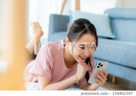 在房間裡操作智慧型手機的年輕女子 在房間裡操作智慧型手機的年輕女子 139402597