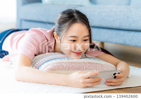 在房間裡操作智慧型手機的年輕女子 在房間裡操作智慧型手機的年輕女子 139402600