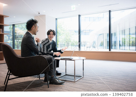A wide-angle, full-body business image of a sales representative conducting a corporate proposal in an office lounge; examples include real estate and professional services. A wide-angle, full-body business image of a sales representative conducting a corporate proposal in an office lounge; examples include real estate and professional services. 139402758