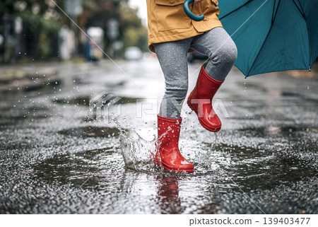 The feet of a child jumping into a puddle on a rainy day 139403477