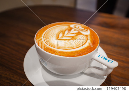Latte art in a white cup: A leaf pattern on a cafe latte viewed from the side. Latte art in a white cup: A leaf pattern on a cafe latte viewed from the side. 139403498