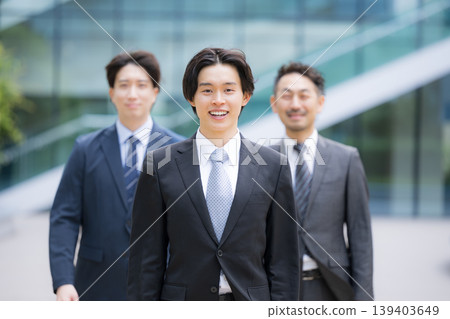A smiling man in a suit walking around conveys a positive image of new graduates and young business teams; suitable for job hunting, career changes, and recruitment. A smiling man in a suit walking around conveys a positive image of new graduates and young business teams; suitable for job hunting, career changes, and recruitment. 139403649