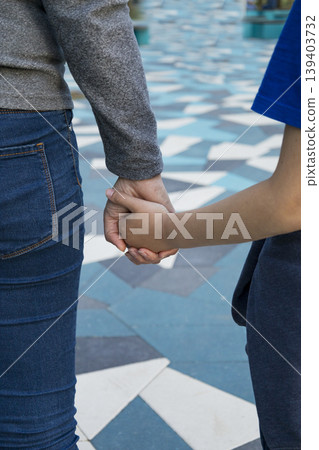 Closeup of couple on city mosaic tiles, Casual couple holding hands amidst textured urban environment, Intimate partners in casual clothing connecting during candid city walk Closeup of couple on city mosaic tiles, Casual couple holding hands amidst textured urban environment, Intimate partners in casual clothing connecting during candid city walk 139403732