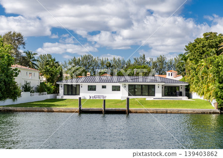 Modern building and green lawn. Residential apartment in waterfront city. City waterfront with house. Vacation building in summer. Luxury waterfront house. Hotel building architecture Modern building and green lawn. Residential apartment in waterfront city. City waterfront with house. Vacation building in summer. Luxury waterfront house. Hotel building architecture 139403862