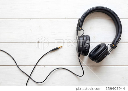 Black headphones placed on a white wood surface Black headphones placed on a white wood surface 139403944