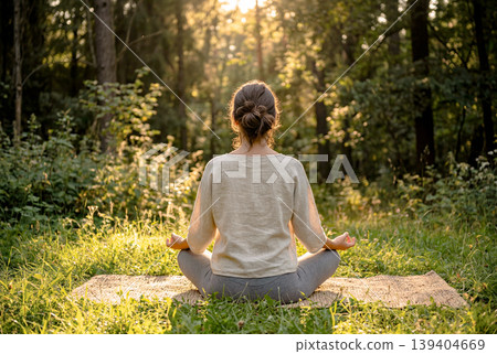 The back view of a woman meditating in the forest 139404669