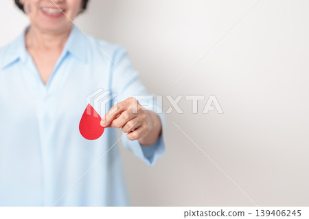 Elderly woman with red Blood drop paper for concept of June World Blood Donor day, Donation, April Hemophilia awareness day, May Thalassemia Day, Anemia awareness, June Sickle Cell and Blood Disorders 139406245