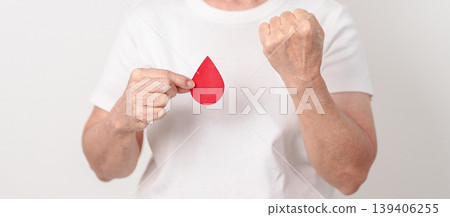 Elderly woman with red Blood drop paper for concept of June World Blood Donor day, Donation, April Hemophilia awareness day, May Thalassemia Day, Anemia awareness, June Sickle Cell and Blood Disorders 139406255