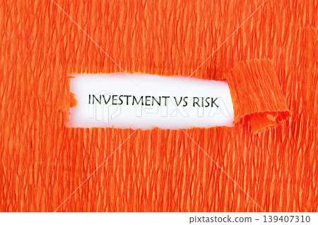 A white space reveals the words Investment Vs Risk through a horizontal rip in vibrant orange textured paper A white space reveals the words Investment Vs Risk through a horizontal rip in vibrant orange textured paper 139407310
