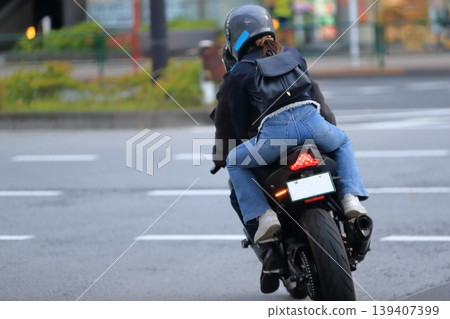 Image of a woman riding a motorcycle with another person. Image of a woman riding a motorcycle with another person. 139407399