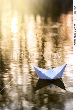 Alone paper boat sailing along the river at sunset. Concept of loneliness, abandonment, freedom 139407842