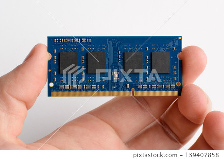 DDR memory card in man`s hand against white background. Upgrading laptop by adding module of RAM memory DDR memory card in man`s hand against white background. Upgrading laptop by adding module of RAM memory 139407858