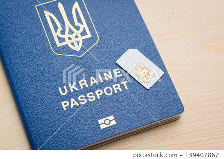 Ukrainian biometric passport and SIM card on a wooden background. Registration and identification SIM card for mobile phone using passport Ukrainian biometric passport and SIM card on a wooden background. Registration and identification SIM card for mobile phone using passport 139407867