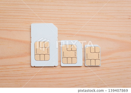 SIM cards of different side on a wooden background. SIM card, micro SIM and nano SIM on table  139407869