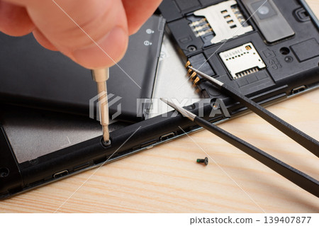 Technician repair mobile phone with a help of screwdriver Technician repair mobile phone with a help of screwdriver 139407877