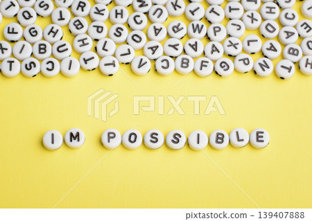 First two letters separated of the word IMPOSSIBLE made of white round plastic blocks on a yellow table First two letters separated of the word IMPOSSIBLE made of white round plastic blocks on a yellow table 139407888