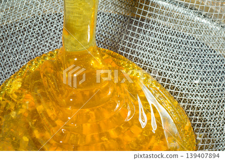 Pouring fresh honey through filter sieve while harvesting Pouring fresh honey through filter sieve while harvesting 139407894