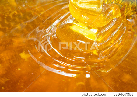Waves of fresh golden honey flowing through the filter sieve Waves of fresh golden honey flowing through the filter sieve 139407895
