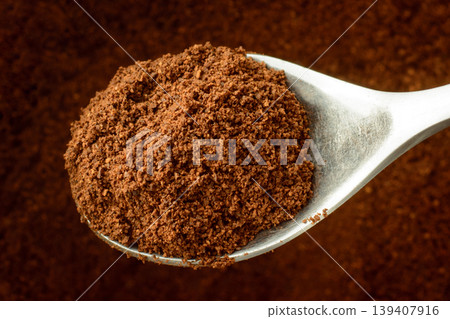Spoon with some ground coffee against a coffee background Spoon with some ground coffee against a coffee background 139407916