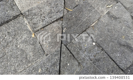 Detailed top view shows dark grey stone tiles with irregular triangular shapes. Textured volcanic rock surfaces create geometric patterns. Perfect for architectural backgrounds, paving design. Detailed top view shows dark grey stone tiles with irregular triangular shapes. Textured volcanic rock surfaces create geometric patterns. Perfect for architectural backgrounds, paving design. 139408531