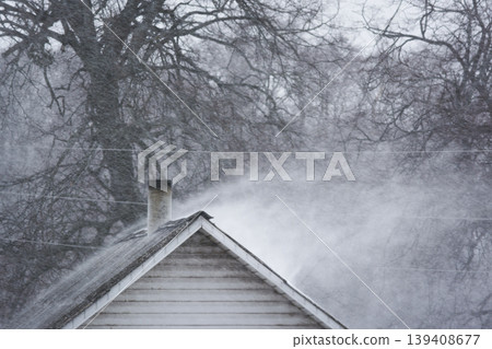 A strong blizzard blows snow from building roof 139408677
