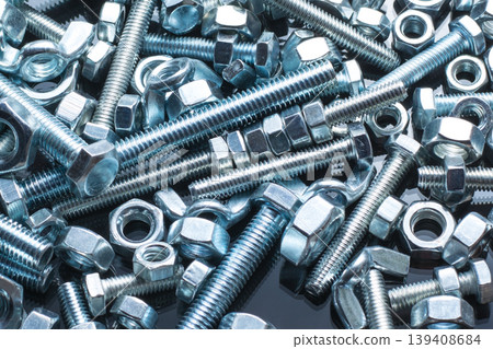 Bolts and nuts of different size on black background Bolts and nuts of different size on black background 139408684