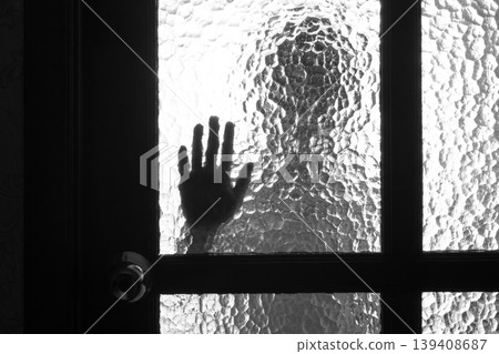 The silhouette of the person and its hand behind the door with the textured glass The silhouette of the person and its hand behind the door with the textured glass 139408687