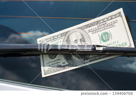 US dollar banknote left on a car under the car wiper on a back window US dollar banknote left on a car under the car wiper on a back window 139408708