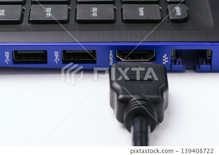 HDMI cable near the HDMI port of the modern blue laptop on a white background. Horizontal shot HDMI cable near the HDMI port of the modern blue laptop on a white background. Horizontal shot 139408722