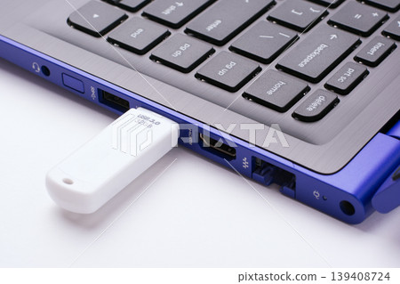 White USB stick plugged in the USB port of the modern blue laptop on a white table White USB stick plugged in the USB port of the modern blue laptop on a white table 139408724