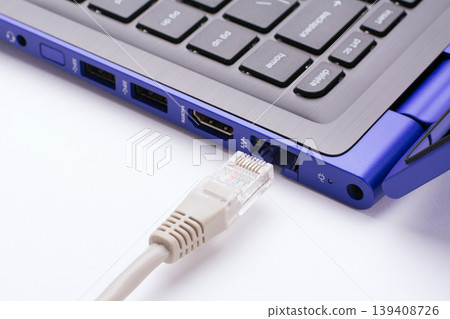 White LAN Internet cable near the port of a modern blue laptop White LAN Internet cable near the port of a modern blue laptop 139408726