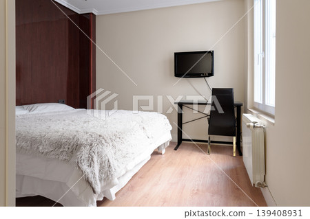 Compact economy hotel room with a minimalist workspace. Double bed and wall mounted TV. Practical budget-friendly interior Compact economy hotel room with a minimalist workspace. Double bed and wall mounted TV. Practical budget-friendly interior 139408931