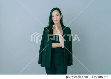 Fashion portrait of a young Japanese woman in a black suit on a gray background 139408956
