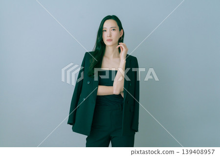 Fashion portrait of a young Japanese woman in a black suit on a gray background 139408957
