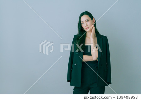 Fashion portrait of a young Japanese woman in a black suit on a gray background 139408958