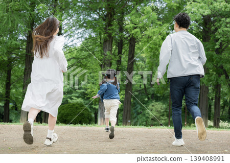 A happy family lifestyle: running and racing in a park surrounded by fresh greenery; a full-body shot of the back without a face. A happy family lifestyle: running and racing in a park surrounded by fresh greenery; a full-body shot of the back without a face. 139408991
