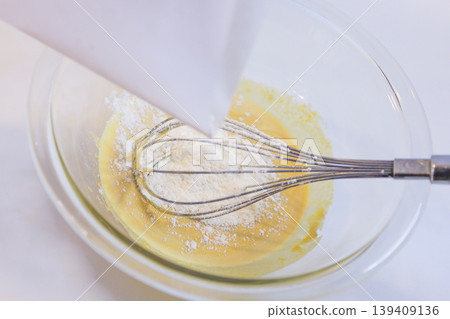 Making custard cream: The process of adding flour to eggs and sugar and mixing. Making custard cream: The process of adding flour to eggs and sugar and mixing. 139409136