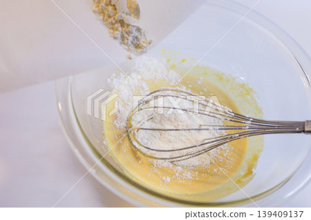 Making custard cream: The process of adding flour to eggs and sugar and mixing. Making custard cream: The process of adding flour to eggs and sugar and mixing. 139409137
