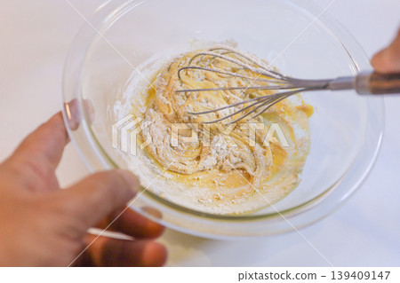 製作蛋奶糊:將麵粉加入雞蛋和糖中攪拌的過程。 製作蛋奶糊:將麵粉加入雞蛋和糖中攪拌的過程。 139409147