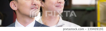 In a factory, a businessman and a worker, both smiling and looking up, gaze towards the future, demonstrating the trusting relationship between the two. In a factory, a businessman and a worker, both smiling and looking up, gaze towards the future, demonstrating the trusting relationship between the two. 139409191