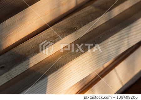 Sunlit pine lumber planks stacked close-up, showcasing natural wood grain, knots Sunlit pine lumber planks stacked close-up, showcasing natural wood grain, knots 139409206