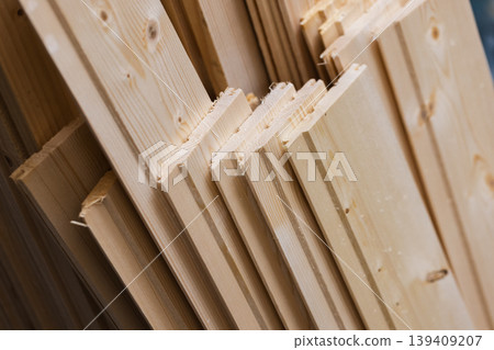 Stacked tongue-and-groove pine planks neatly arranged in a workshop Stacked tongue-and-groove pine planks neatly arranged in a workshop 139409207