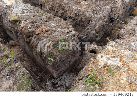 Excavated trenches with lifted sod blocks and exposed roots at a construction site Excavated trenches with lifted sod blocks and exposed roots at a construction site 139409212