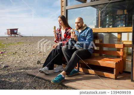 Cute couple eating ice cream together near cafe 139409939