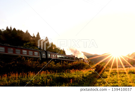 The SL Banetsu Monogatari train runs bathed in the setting sun. 139410037