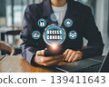Businesswoman using smartphone for access control, surrounded by digital security icons in a modern office setting. 139411643