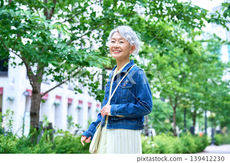 Senior woman strolling along a greenway in the city Senior woman strolling along a greenway in the city 139412230